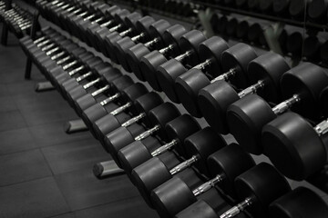 Black dumbbell set. Close up many metal dumbbells on rack in sport fitness center