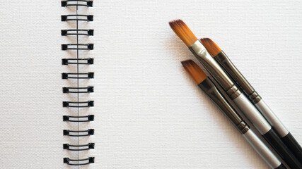 Open canvas pad with a paintbrushes.