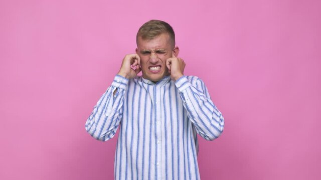 Young caucasian man covering ears with hands