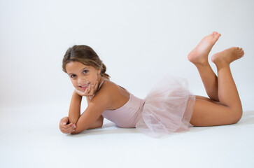 Obraz premium Beautiful little ballerina on floor doing stretching over white background