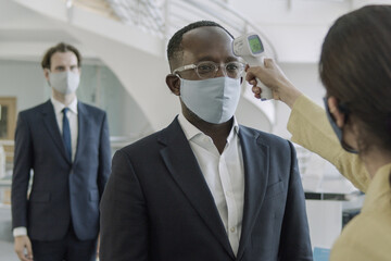 Business executives having temperature checked at reception of office