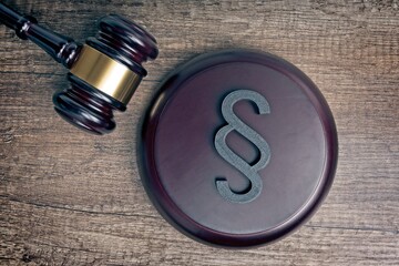 Wooden judge's gavel beside a paragraph / section sign as a symbol for the idea of Justitia and...