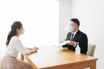Fototapeta premium フェイスシールドとマスクをして商談をするビジネスパーソン