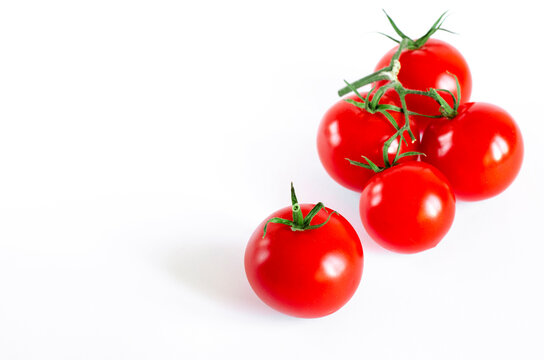 A branch of cherry tomatoes lies on a white background