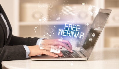 Side view of a business person working on laptop with FREE WEBINAR inscription, modern business concept