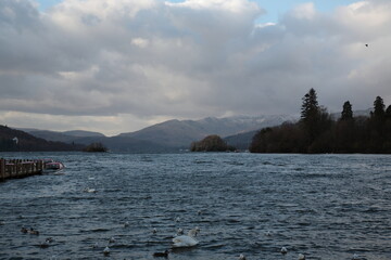 View of Lake Windermere with snow mountains and boats floating on water during early Spring at Bowness-on-Windermere, Windermere, Lake District National Park, Cumbria, England UK