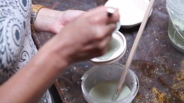 hands pouring glaze on the bowl