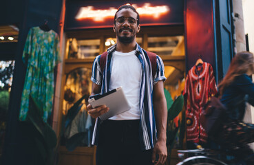 Smiling young ethnic man using smartphone on street