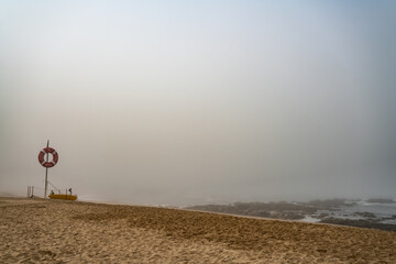 Naklejka na ściany i meble Magische-Mystische Strandlandschaft. Nebel, Fog, Mist, Wolken am Stand mit Menschen in der Distanz und Blick auf den ewigen Ozean.