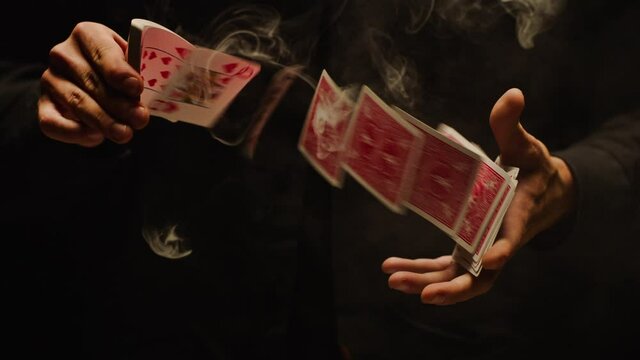 Close-up of a Magician's Hands Performing Card Trick . Throwing and Catching Cards in the Air on black Background with smoke . Card Mechanic .  Shot on ARRI Alexa cinema camera in Slow Motion . 200fps