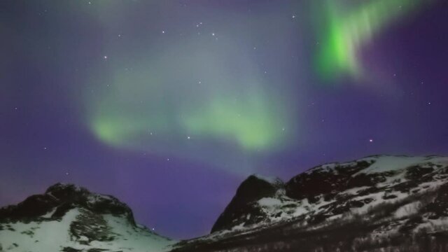 Bright aurora borealis dancing over a mountain pass, SLOW PAN LEFT TO RIGHT.