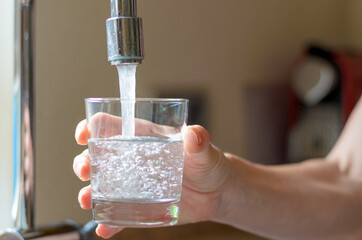 Woman filling a glass of water from a tap