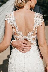 closeup shot of newlyweds hands on the back of the brides beautiful white wedding dress