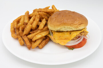 Delicious Fried Chicken Sandwich with Cheese Tomatoes Lettuce and Onions with a Side of French Fries on a White Plate
