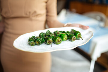 Waitress holding grilled spanish padron peppers