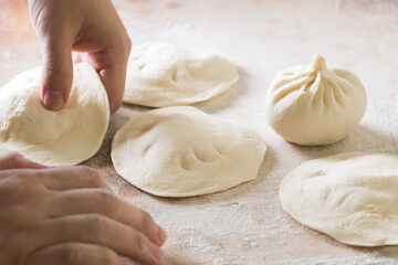 Image of making process of Chinese traditional food - baozi ( Chinese steamed buns ). Using a rolling pin and flatten the dough into a round thin wrapper approx.