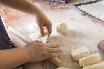 Image of making process of Chinese traditional food - baozi ( Chinese steamed buns ). Using a rolling pin and flatten the dough into a round thin wrapper approx.