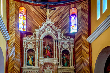 Fototapeta na wymiar Guaranda, Bolivar Province, Ecuador - November 2013: Guaranda's cathedral altar piece and frontal area, with religious decorations and statues, stained windows, steps and arches. Daytime.