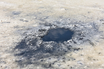 Crystallized salt and natural mineral mud in a dried salt lake. Here people take mud baths because...