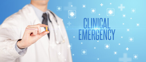 Close-up of a doctor giving a pill with CLINICAL EMERGENCY inscription, medical concept