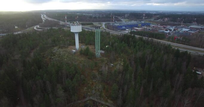 Aerial circling of water tower and district heating plant's smokestacks near Hakunila, Vantaa, Finland, during fall.