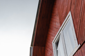Wall with a window of a wooden house against the sky.