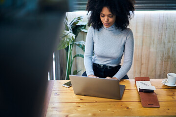 Serious black woman with laptop in cafe