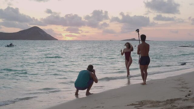 photographers shooting model in bikini on the beach at sunrise