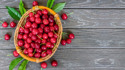 ripe cherries in a basket and on a wooden background top view. cherries and copy space. background with a harvest of ripe sweet cherries.