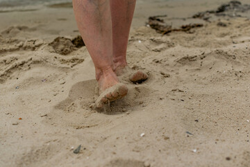 Feet naked barefoot without shoes burrow in the sand on a sandy beach, white skin and toes make movements