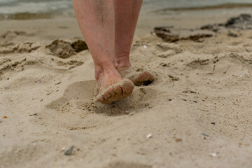 Feet naked barefoot without shoes burrow in the sand on a sandy beach, white skin and toes make movements