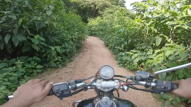 Biker riding offroad in a dense green alley riding to the mountain at Parasnath Hill in Jharkhand, India.