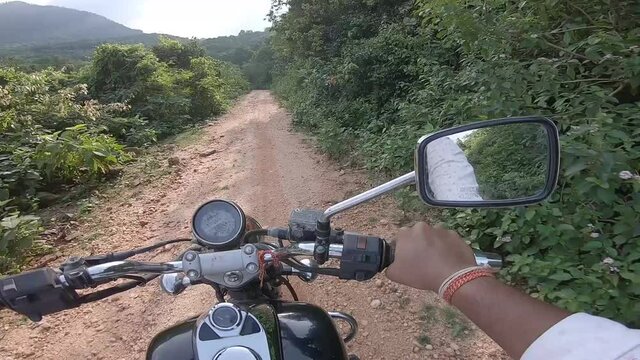 Biker riding offroad in a dense green alley riding to the mountain at Parasnath Hill in Jharkhand, India.