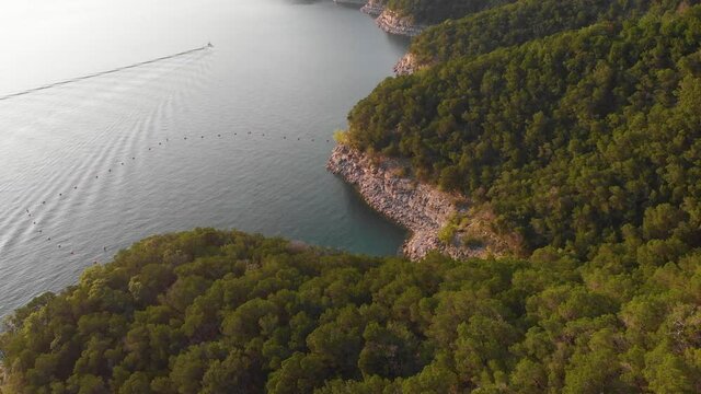 Slow Vertigo Pan Along The Cliffs Of Lake Travis. A Boat Can Be Seen On The Lake Creating Aesthetic Ripples On A Glass Lake.