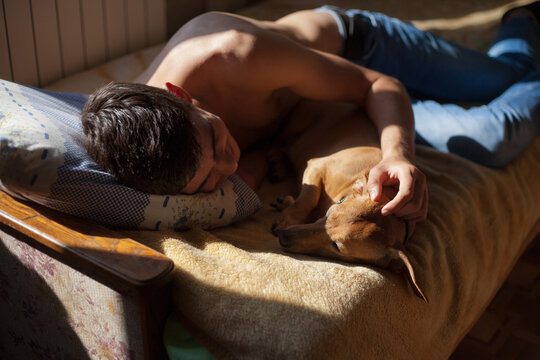 a guy ies on a bed with a dog