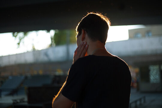 backside portrait of a guy in the backlight against a skate park