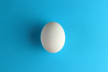One white egg on a blue background. The concept of calorie content, life, healthy nutrition, Easter