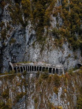 Old abandoned road passes by the mountain cliff with a river downside