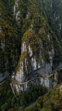 Old abandoned road passes by the mountain cliff with a river downside