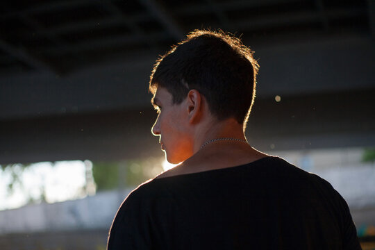photo of a guy in a black T-shirt in backlight - Powered by Adobe