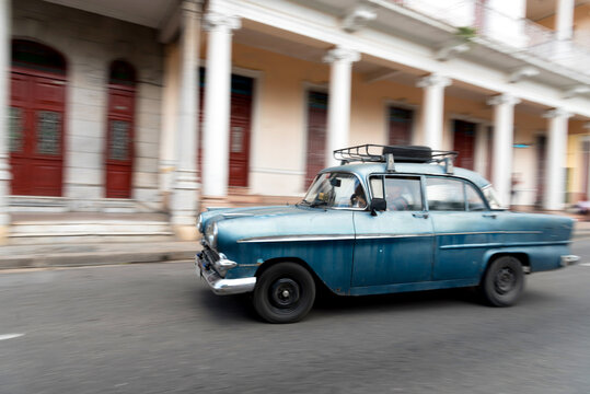 Classic Car Passing At Top Speed In Front Of A Colonial Mansion