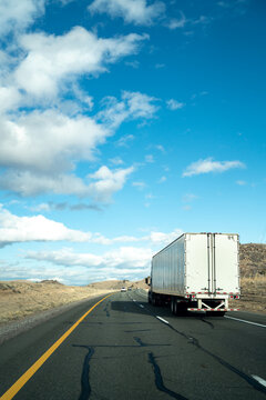 A semi truck driving down the freeway on a blue sky day
