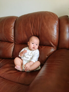 portrait of cute baby girl sitting on sofa