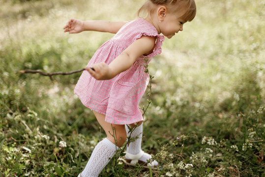 Toddler Girl Is Playing Outside On The Summer Day