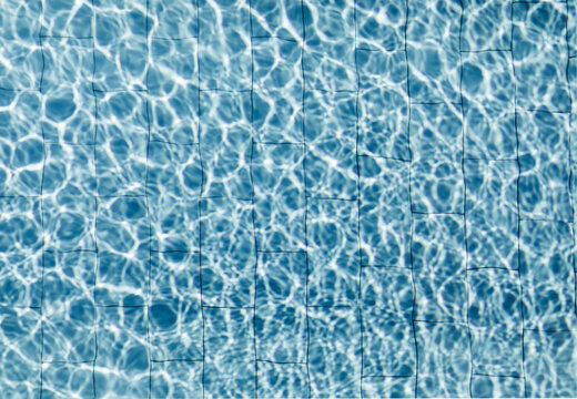 Overhead sight of swimming pool pavement tiles distorted by water refraction