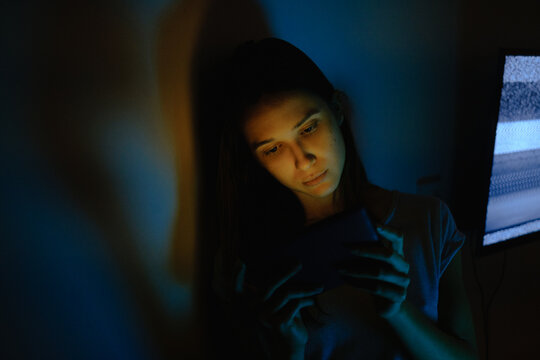 Young woman lit with tablet screen light