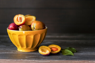 yellow ripe plums in a yellow bowl on a wooden background. fresh plums close-up. background with plums in a bowl close-up.