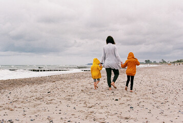 Mother and Children Walking Barefoot on Beach