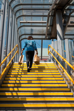 Afro woman going back home after a shopping day. Walking on stairs.