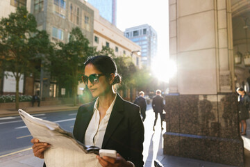 Elegant business woman reading the newspaper in the street
